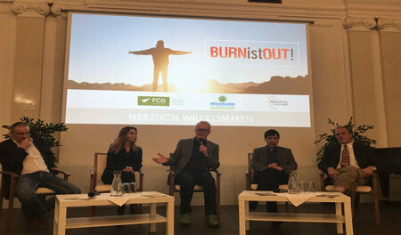 Bühne mit fünf Speakern und Leinwand im Hintegrund.