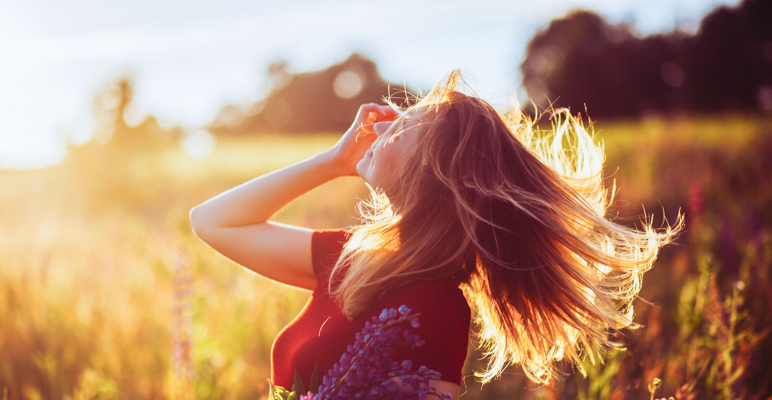 Frau in der Sonne mit Blumen in der Hand.